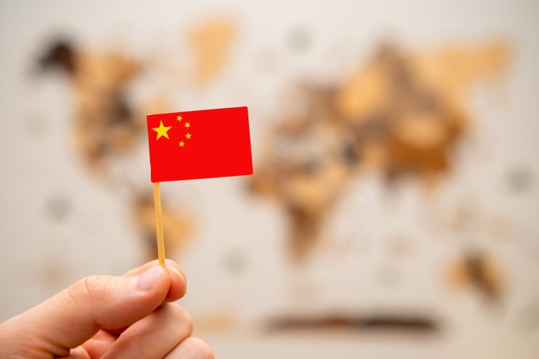 China flag in mans hand on the world map background.