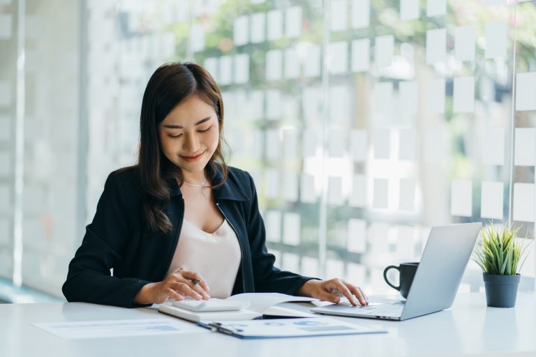 Smiling Young Asian Business women working with calculator, business document and laptop computer